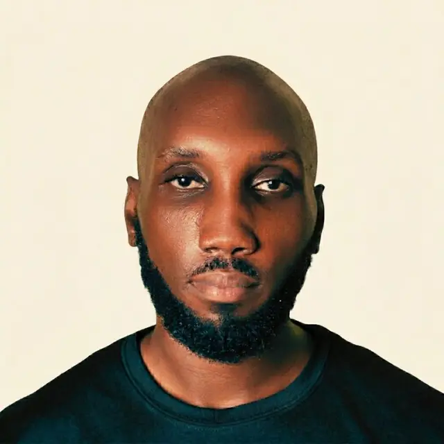 Ato Sam, head-and-shoulders portrait against a cream background.